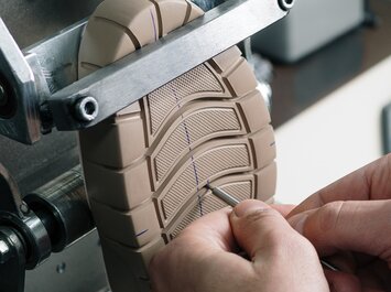 Deux mains vérifient la semelle d’une chaussure dans une machine. | © Gabor Shoes GmbH, Allemagne