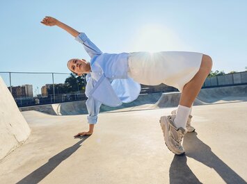 Une femme en vêtements clairs et baskets sportives effectue un mouvement dynamique dans un skatepark sous le soleil. | © Gabor Shoes GmbH, Allemagne