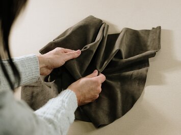 Deux mains tiennent et touchent un morceau de cuir marron. | © Gabor Shoes GmbH, Allemagne