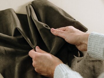 Deux mains tiennent et touchent un morceau de cuir marron. | © Gabor Shoes GmbH, Allemagne