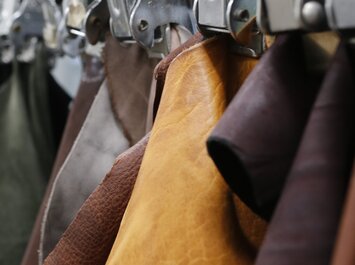 Plusieurs morceaux de cuir de différentes couleurs sont suspendus en rangée, triés par des pinces métalliques. | © Gabor Shoes GmbH, Allemagne