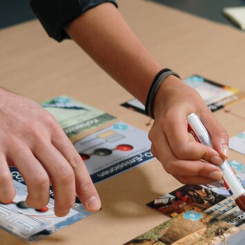 Deux personnes travaillent à une table et organisent des cartes d’information, une personne tient un stylo. | © Gabor Shoes GmbH, Allemagne