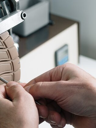 Gros plan sur des mains qui travaillent une semelle de chaussure claire à un dispositif métallique. | © Gabor Shoes GmbH, Allemagne