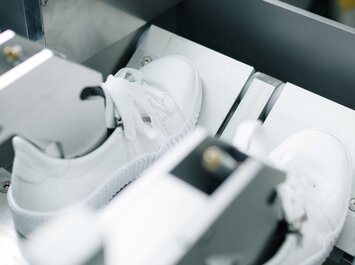 Deux baskets blanches sont fixées côte à côte dans une machine de test. | © Gabor Shoes GmbH, Allemagne