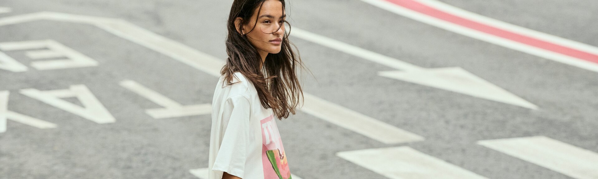 Une femme traverse un passage piéton et porte un t-shirt blanc avec un imprimé coloré. La rue présente des marquages voyants. | © Gabor Shoes GmbH, Allemagne