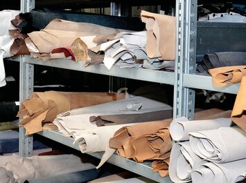 Plusieurs peaux de cuir roulées de différentes couleurs rangées sur des étagères.