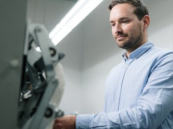 Un homme en chemise bleu clair utilise une machine dans une pièce bien éclairée. | © Gabor Shoes GmbH, Allemagne