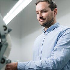 Un homme en chemise bleu clair utilise une machine dans une pièce bien éclairée. | © Gabor Shoes GmbH, Allemagne