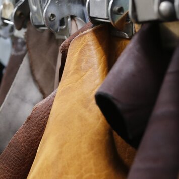 Plusieurs morceaux de cuir de différentes couleurs sont suspendus en rangée, triés par des pinces métalliques. | © Gabor Shoes GmbH, Allemagne