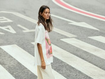 Une femme traverse un passage piéton et porte un t-shirt blanc avec un imprimé coloré ainsi qu’un pantalon clair. La rue présente des marquages voyants. | © Gabor Shoes GmbH, Allemagne