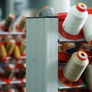 Plusieurs bobines de fil de différentes couleurs alignées.