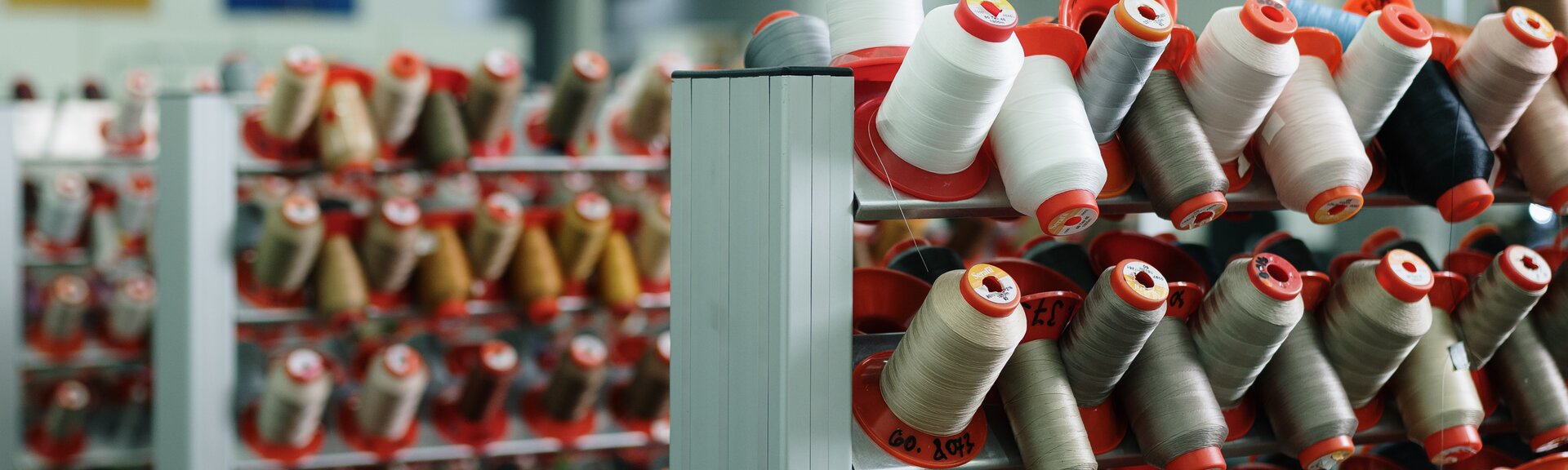 Plusieurs bobines de fil de différentes couleurs alignées.