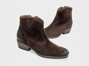 Donkerbruine dames-enkelboots van suède in westernstijl met lage blokhak en licht vierkante neus, vrijstaand tegen een witte achtergrond. | © Gabor Shoes GmbH, Duitsland