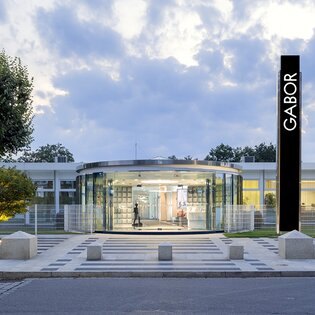 A modern office building with a glass façade and a large Gabor logo at the entrance. | © Gabor Shoes GmbH, Germany