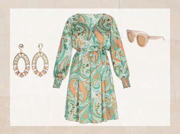Une robe à motifs colorés à manches longues en vert et orange est mise en avant. À gauche, des boucles d’oreilles ovales voyantes avec des strass, à droite, des lunettes de soleil beiges à monture large. Tous les objets sont présentés sur un fond clair. | © aboutyou.de 