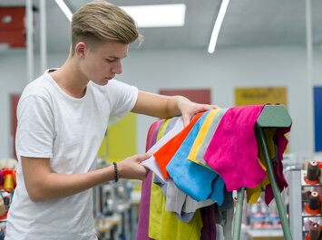 Personne examine des pièces de cuir colorées dans un atelier. | © Gabor Shoes GmbH, Allemagne