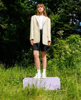 Personne debout sur l’herbe avec blazer clair, short et baskets. | © Gabor Shoes GmbH, Allemagne