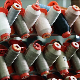 Plusieurs bobines de fil de différentes couleurs alignées.