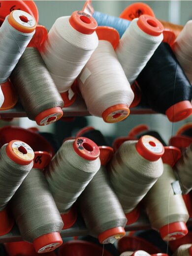 Plusieurs bobines de fil de différentes couleurs alignées.