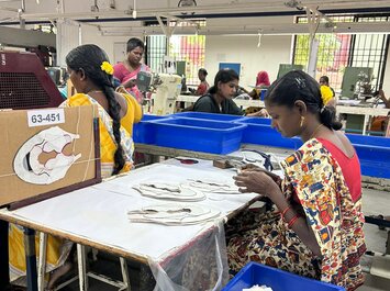 Femmes travaillant dans une usine de chaussures, assemblant des pièces de chaussures à une table de travail. | © Gabor Shoes GmbH, Allemagne