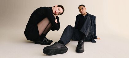 Gabor Women’s Shoes | A man and a woman sit casually on the floor, wearing black men’s sneakers and black women’s loafers – Autumn/Winter 2026 | © Gabor Shoes GmbH, Rosenheim